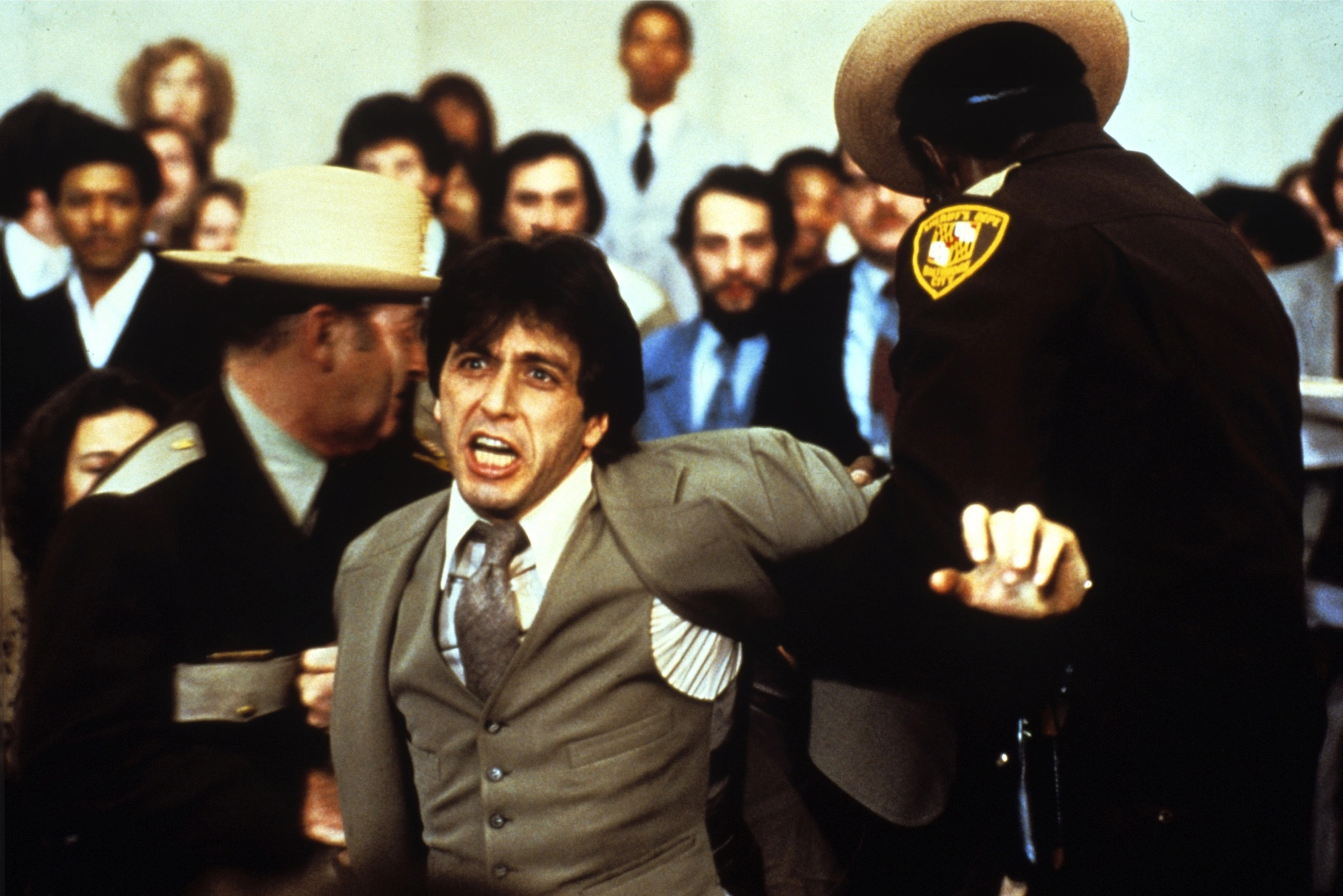 Post cover: Al Pacino as Arthur Kirkland in And Justice for All (1979) is being forcefully restrained by a police officer in a courtroom, his face showing intense emotion. The background is filled with blurred spectators, capturing the chaotic and dramatic atmosphere of the scene.